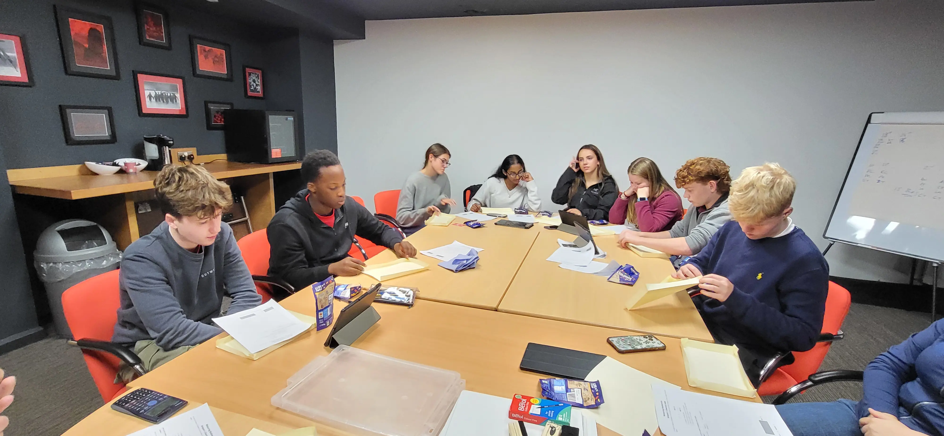 Rendcomb College year 12 students sat around a table learning about geography in a classroom